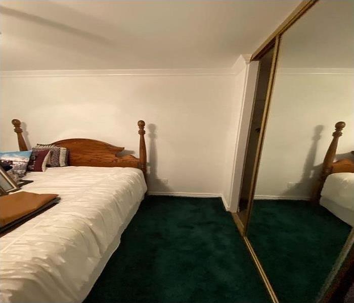 white walls, green carpet bed in center of room